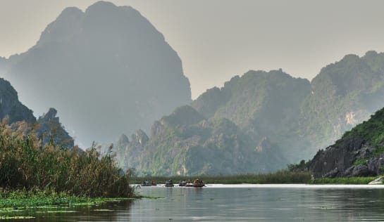 Mekong mit Booten und Bergen im Hintergrund