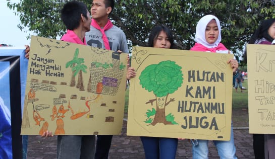 Junge Leute mit selbsgemalten Plakaten. Auf einem steht: Nehmt den Tieren nicht ihre Rechte. Auf dem anderen: Der Wald ist auch unser Wald