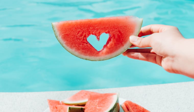Wassermelone mit einem eingeschnittenen Herz vor Pool