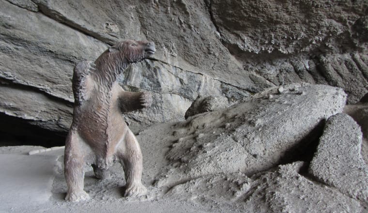 Die Skulptuer eines urzeitlichen Riesenfaultiers steht aufgerichtet vor dem Eingang einer Höhle in Chile