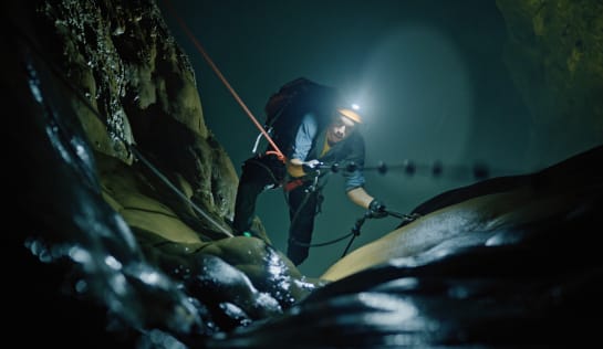 Und gleich am Anfang geht es 100 Meter senkrecht nach unten Tobi zieht sich am Kletterseil nach oben, Richtung Zuschauer, er trägt einen Rucksack und am Helm eine Lampe