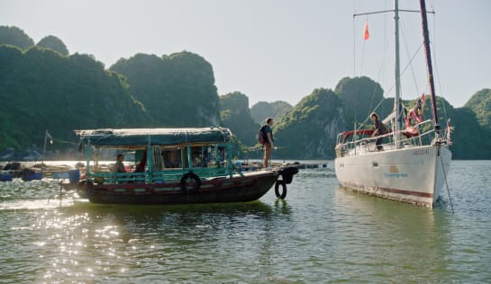 Wie durch ein Wunder findet Tobi das Boot seiner Freundin Marina... Tobi steht auf einem alten traditionellen Fischeerboot und schaut auf ein weißes Segelboot