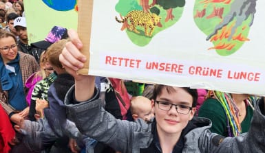 Alltagstipps für den Schutz der Regenwälder und der grünen Lunge ein Teenager hält ein Regenwaldschutz-Plakat in die Kamera mit der Aufschrift Rettet unsere grüne Lunge