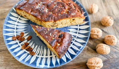 tahini-kuchen Angeschnittener Kuchen auf einem blau-weiß gemustertem Teller mit Walnüsse auf der Tischplatte