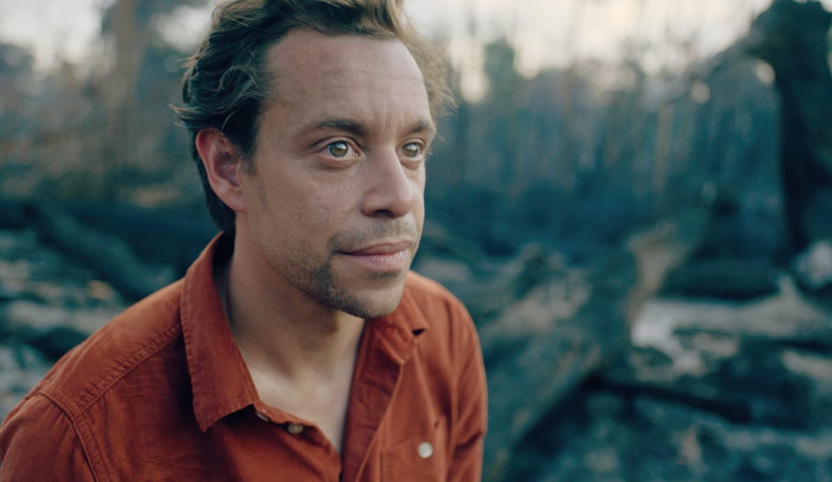 Erschüttert steht Tobi vor dem abgebrannten Regenwald der Jupaú-Gemeinschaft Checker Tobi steht traurig auf abgrebranntem Regenwald