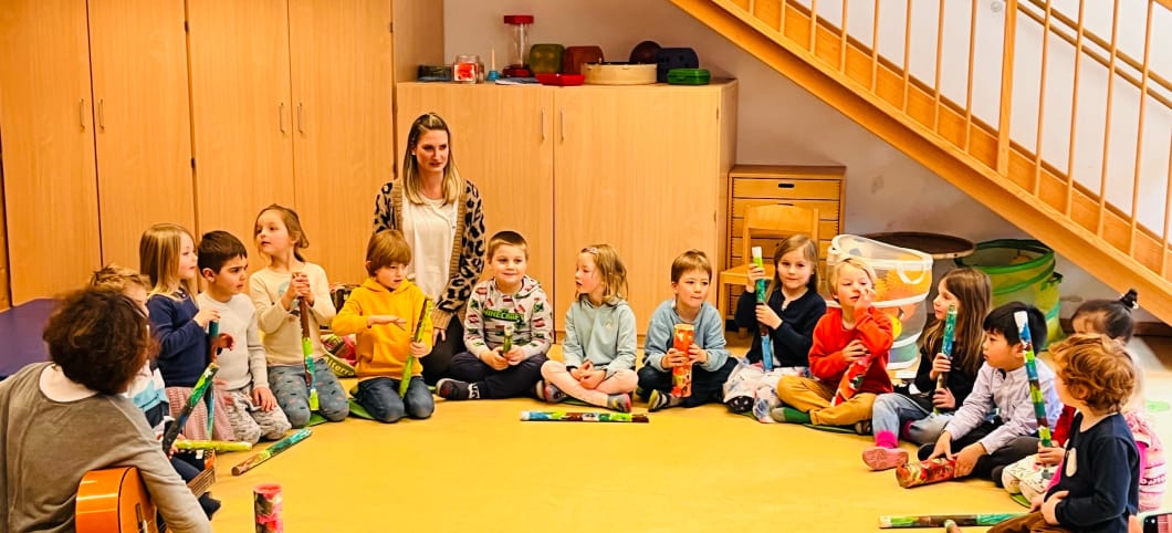 Kinder sitzen im Kreis, einige haben Instrumente