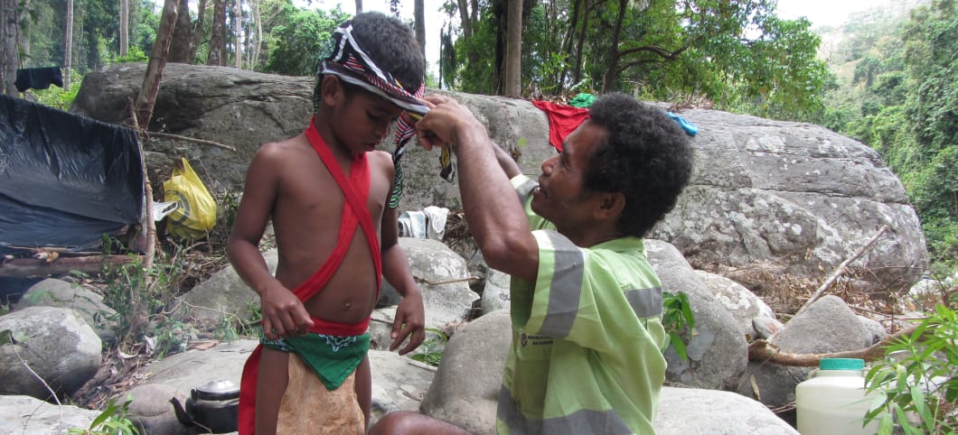 Vater der indigenen Batak setzt seinem Sohn einen Haarraeif aus Ästen auf. 