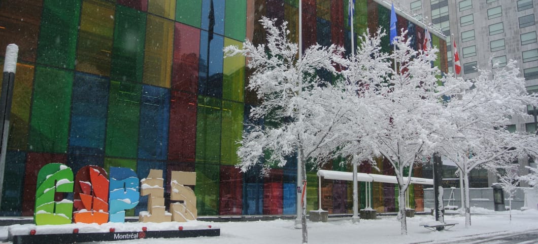Schriftzug COP15 vor dem Kongress-Zentrum in Montréal. Davor kleinere schneeweiße Bäume