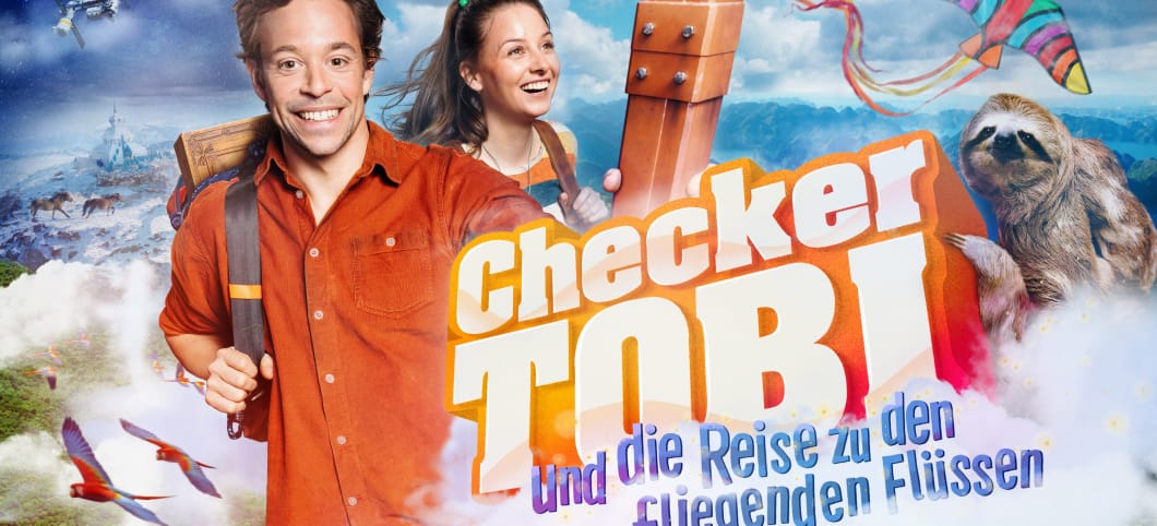 Das Kinoplakat für "Checker Tobi und die Reise zu den fliegenden Flüssen" Tobi und Marina lachend, zu sehen sind außerdem ein Faultier, ein Papiervogel und Papageien, im Hintergrund schäumendes Meer. Auf dem Plakat steht der Titel: Checker Tobi und die Reise zu den fliegenden Flüssen