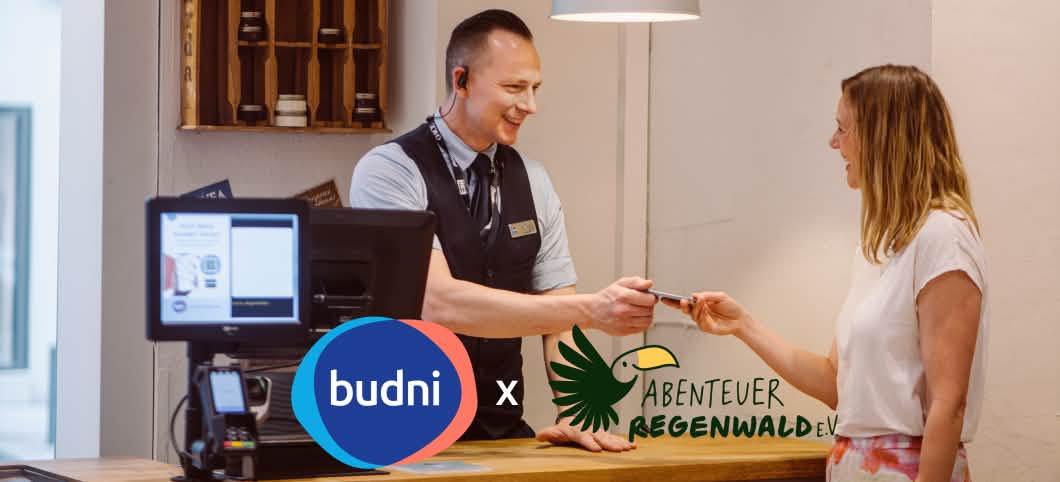 Ein Budni Mitarbeiter nimmt ein Handy zur Sammlung für das Recycling zum Schutz der Regenwälder entgegen