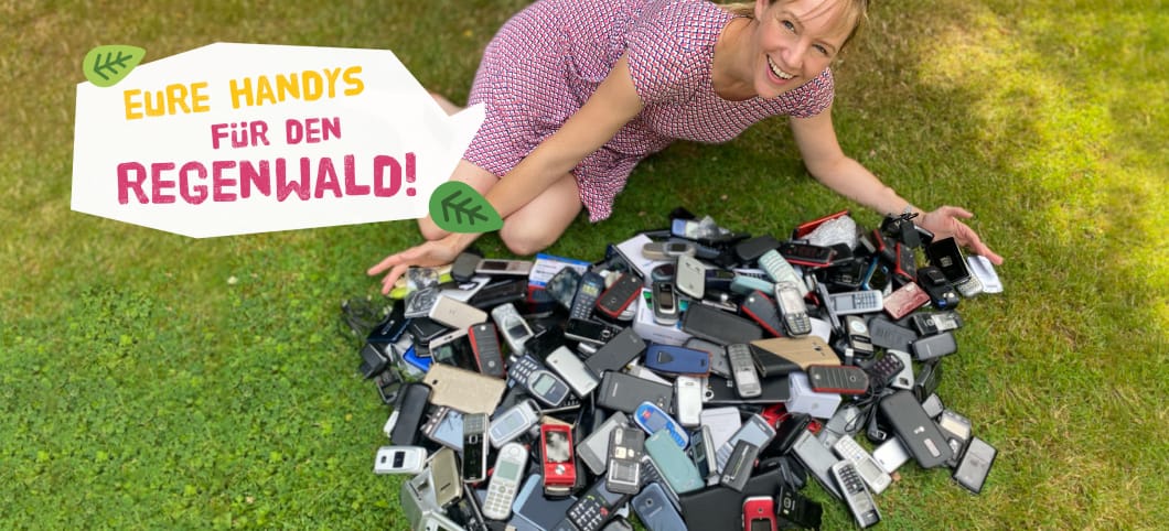 Kathrin von Abenteuer Regenwald liegt auf dem Rasen vor hunderten zum Recycling eingeschickten Handys