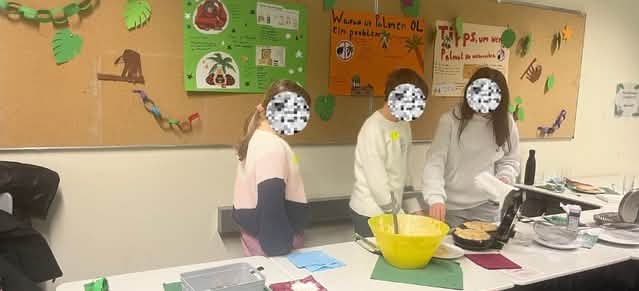 Drei Kinder stehen an einem Tisch und backen Waffeln.