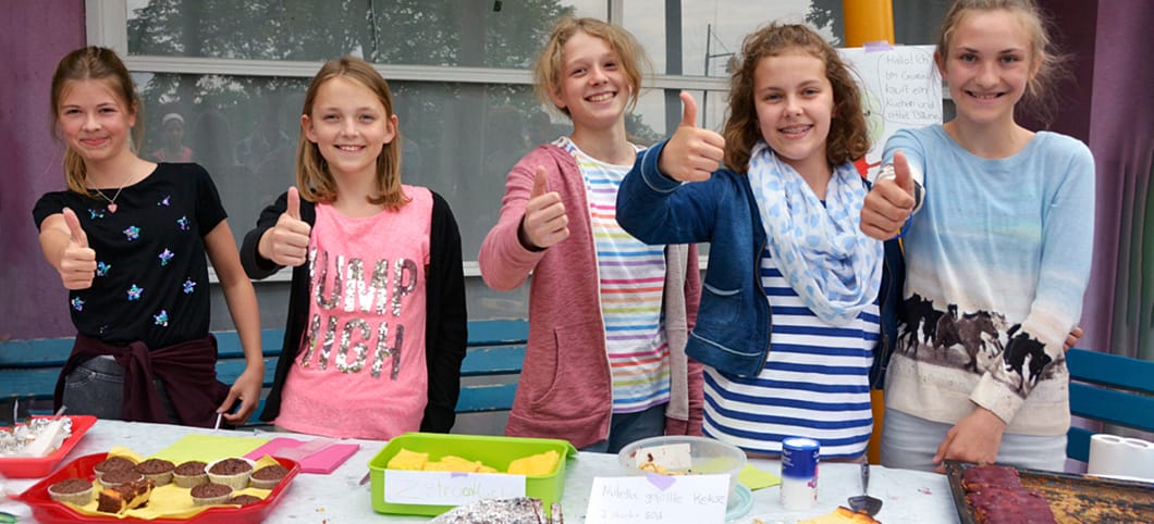 Fünf Schüler stehen vor einem Kuchenbasar als Spendenaktion zugunsten des Regenwaldes