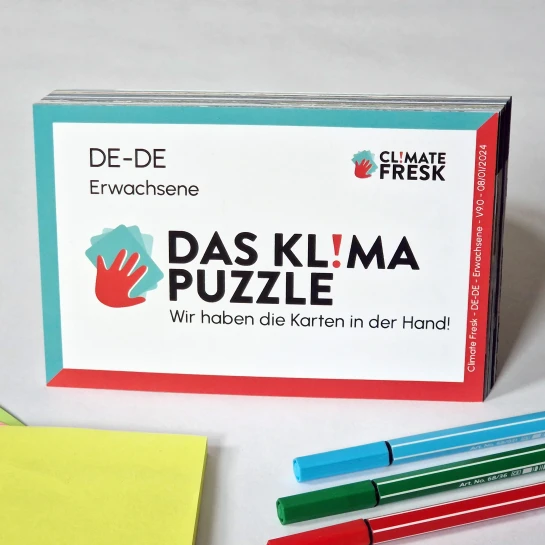 Karton mit dem Klima-Puzzle, davor Stifte und Zettel